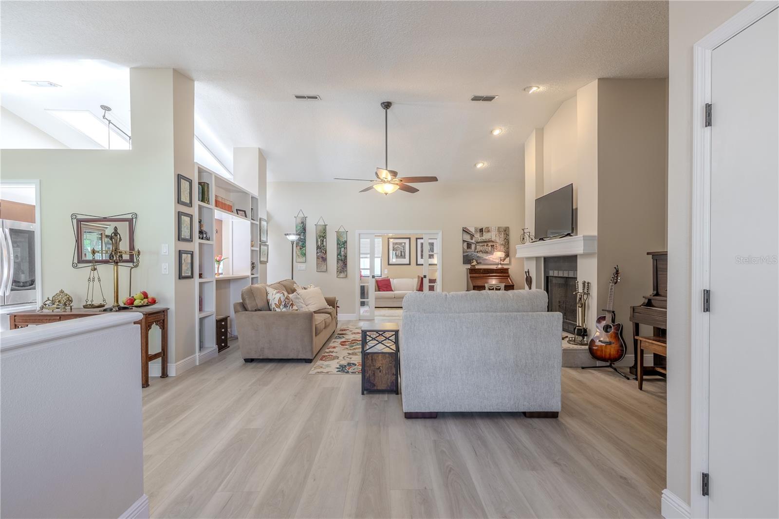 The spacious living room offers a bright and welcoming atmosphere, enhanced by fresh interior paint and brand-new luxury vinyl plank flooring (2025). Vaulted ceilings and recessed lighting add to the sense of openness, while a centrally mounted ceiling fan keeps the space comfortable year-round.