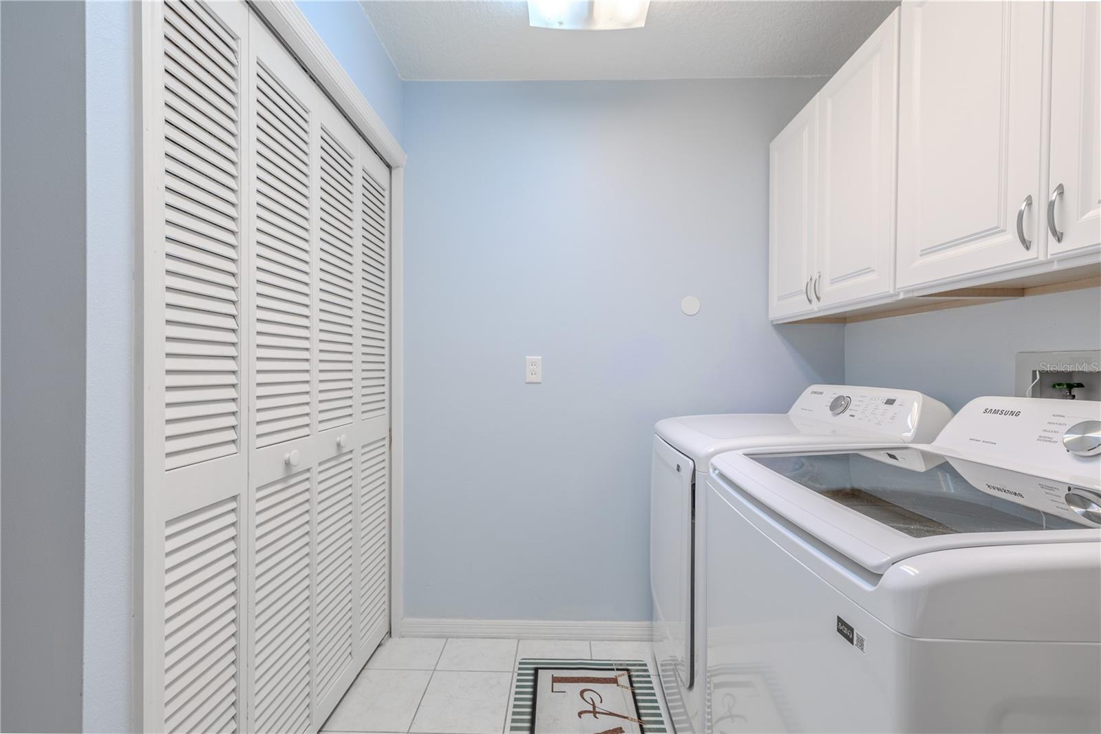 A deep utility sink adds extra functionality, while the soft blue walls and tiled floor keep the space fresh and inviting. A wall of louvered doors conceals even more storage, making this laundry area as organized as it is attractive.