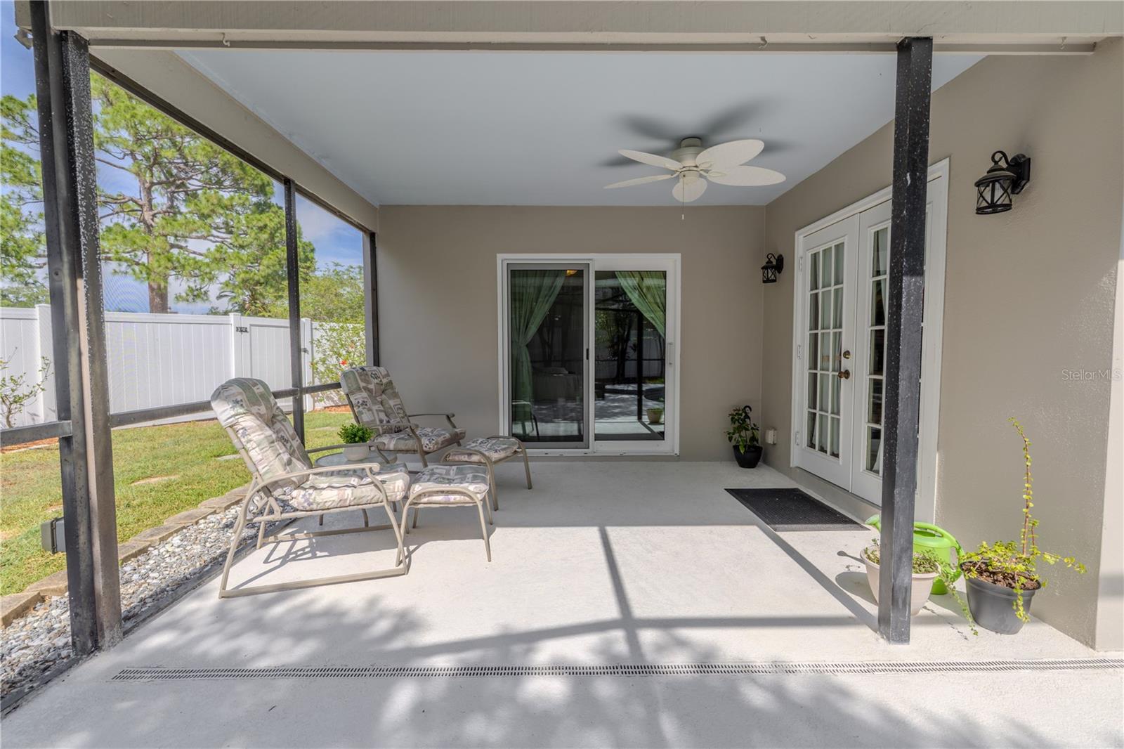 The covered patio area is equipped with ceiling fans and multiple access points from the home,  a shaded retreat with views of the privacy-fenced backyard.