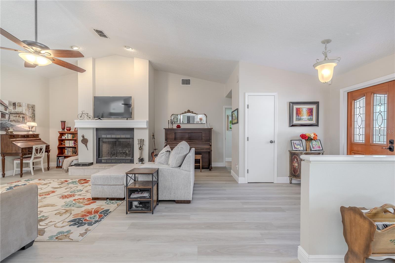 A cozy wood-burning fireplace with a classic mantle serves as a focal point, bringing warmth and charm to the room. A wide entryway provides a seamless connection to the adjacent flex space