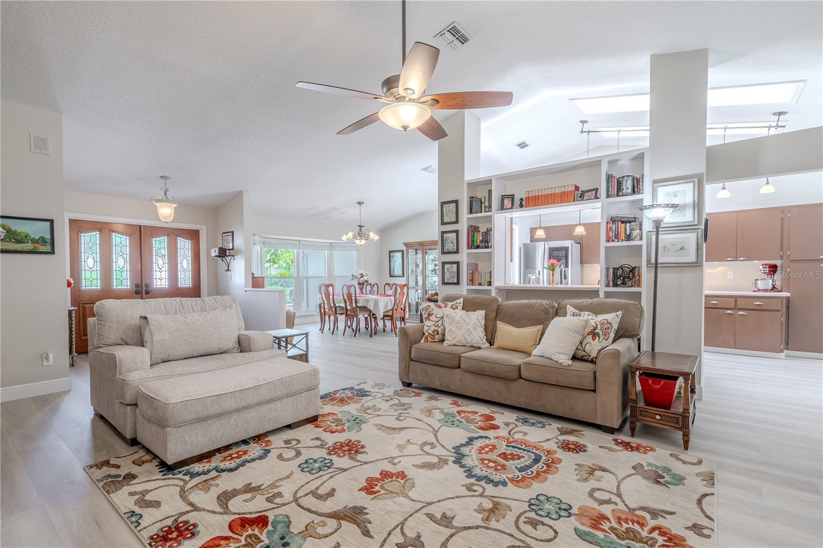 Living room: A ceiling fan adds comfort and efficiency, and the open sightlines connect seamlessly to the dining area and kitchen, making it ideal for entertaining and everyday living. The triple glass front door with decorative inserts adds a grand touch to the entry while flooding the space with soft natural light.