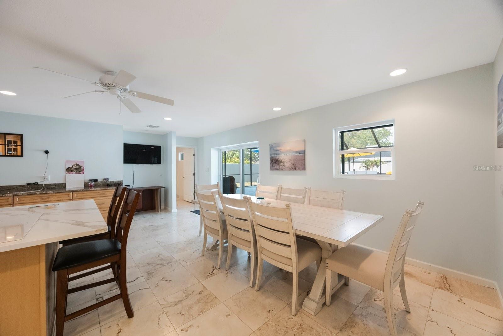 The heart of this home is undoubtedly its impressive kitchen, centered around a generous island that boasts a convenient stovetop and invites casual gatherings. From this vibrant hub, and the adjoining dining space, expansive sliders provide direct access to a sparkling, screened-in pool, making indoor-outdoor enjoyment a daily pleasure.