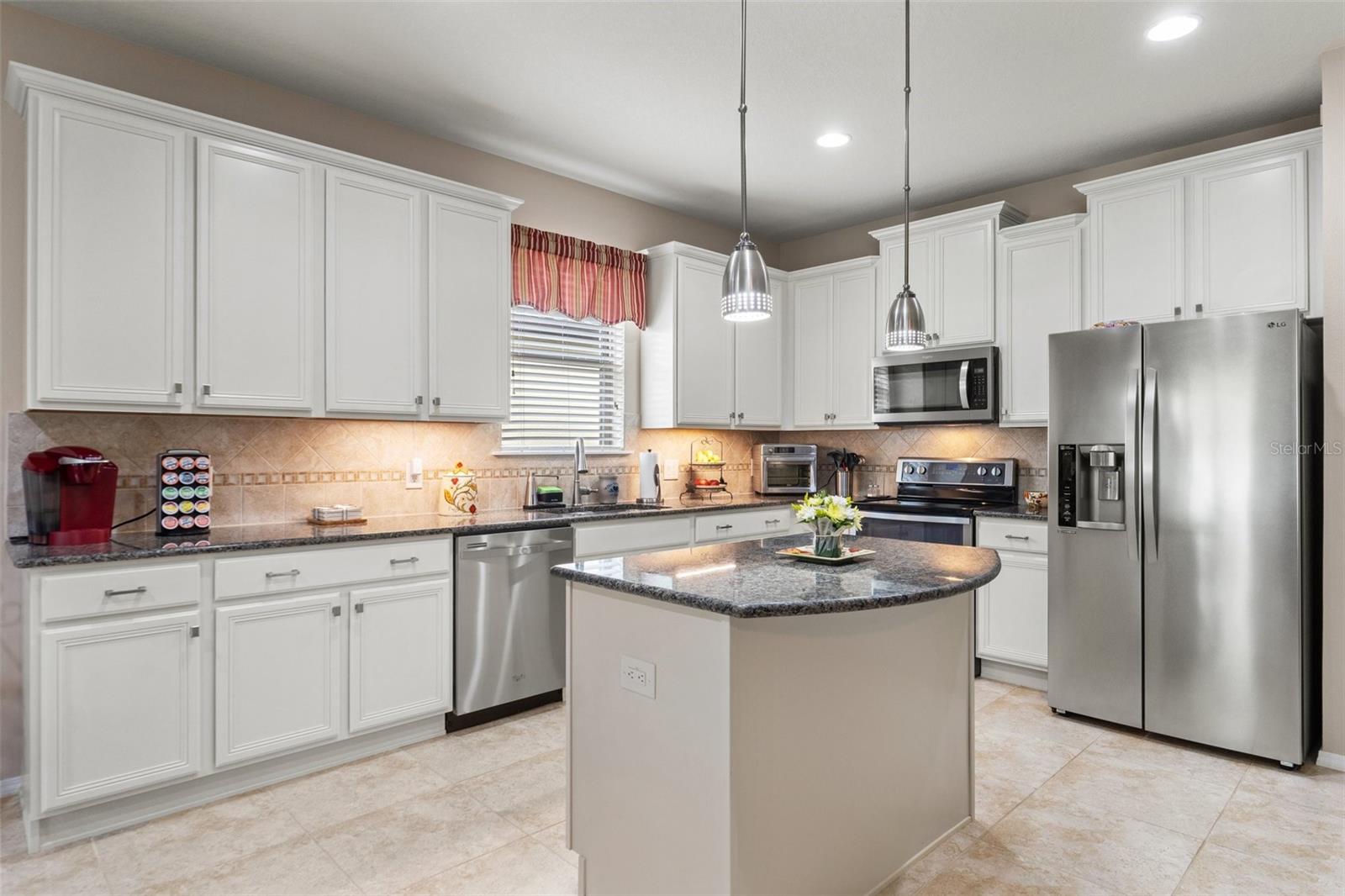 Kitchen with tall 42" cabinets, soft close drawers w/pull outs, tile backsplash from countertop to the cabinets, granite countertops, island and a pantry.  All the SS Appliances stay!