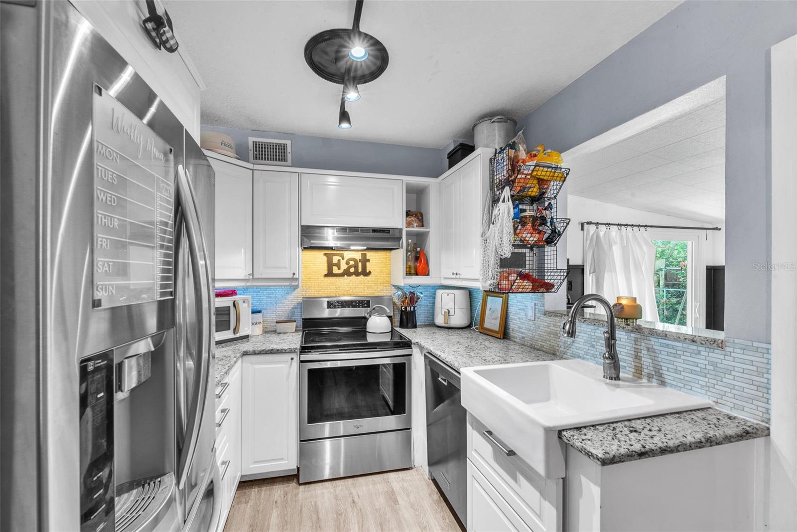 The kitchen has been beautifully updated with a granite countertop, a stylish apron-front farmhouse sink, and upgraded stainless steel appliances.