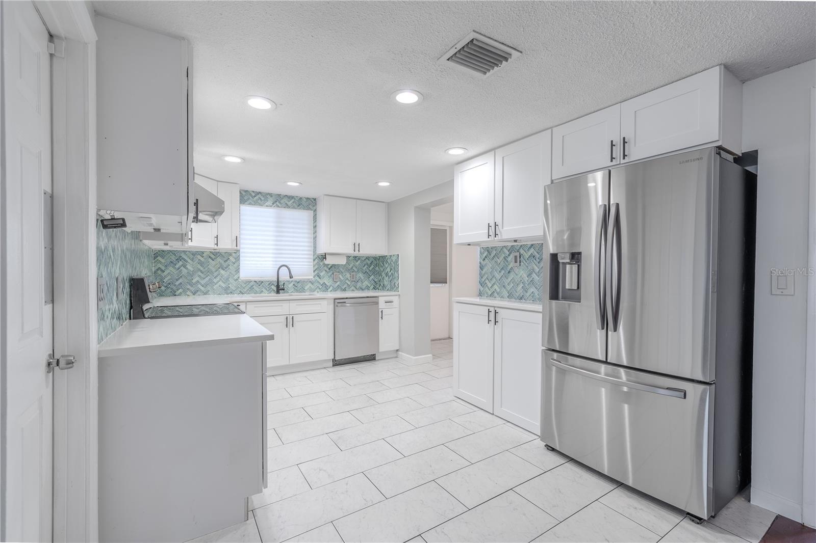 Stainless steel appliances, including a French door refrigerator, built-in dishwasher, and glass-top range, make this kitchen as practical as it is stylish.