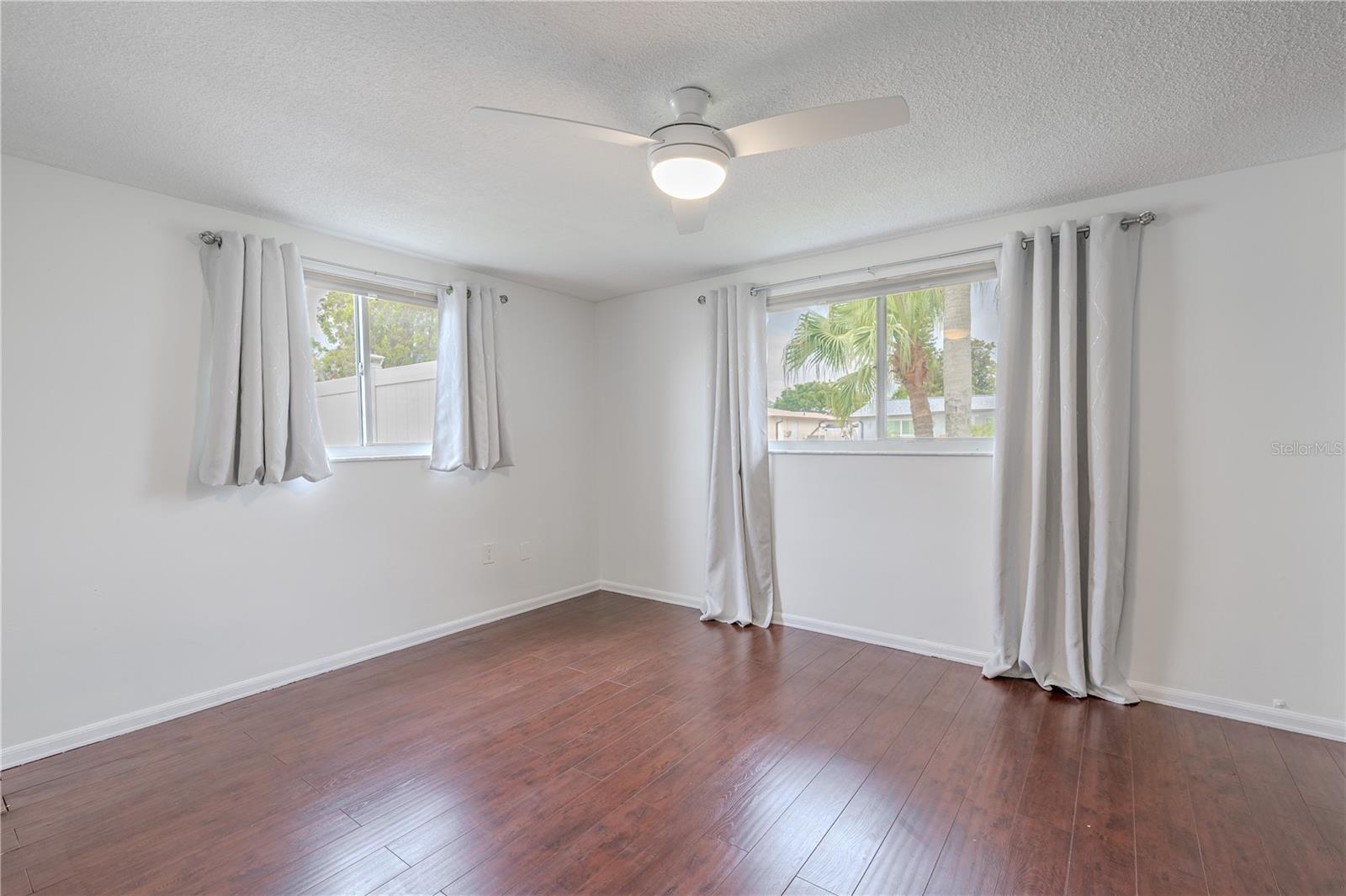 The second bedroom offers comfort, and functionality in one light-filled space. With two windows on adjacent walls, the room enjoys beautiful natural light and gentle cross-breezes, while a ceiling fan adds year-round comfort. The wood-look flooring continues the warm, cohesive feel found throughout the home.