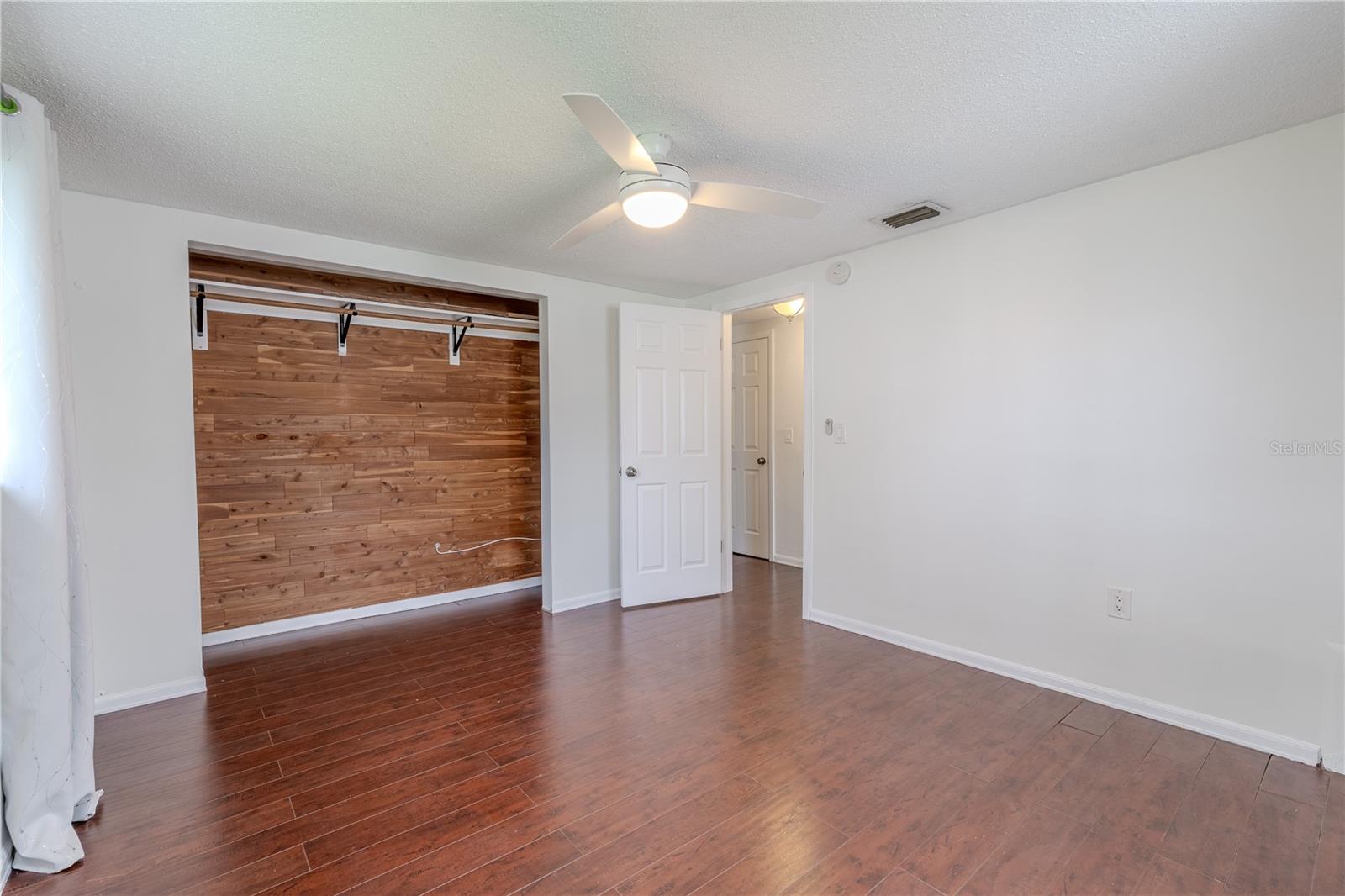 2nd bedroom's  unique feature is the open closet with a striking wood accent wall—both practical and stylish—providing a custom feel and ample storage.
