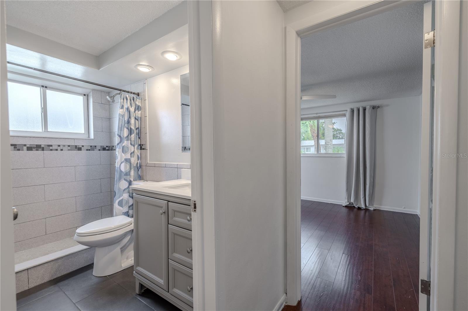 The second full bathroom offers stylish updates and a thoughtful layout, making it perfect for guests or daily use. Featuring a spacious walk-in shower with modern tilework, a decorative mosaic accent border, and a built-in niche for storage, this bath is as functional as it is attractive.