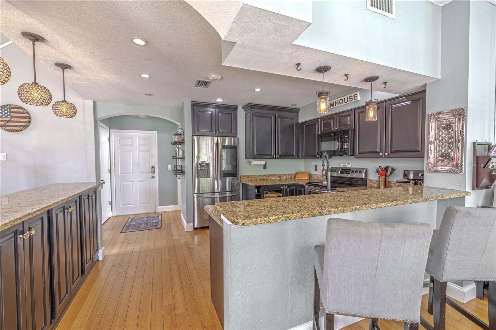The wraparound breakfast bar offers generous counter space for meal prep and casual dining, and the layout maximizes storage with both upper and lower cabinetry.