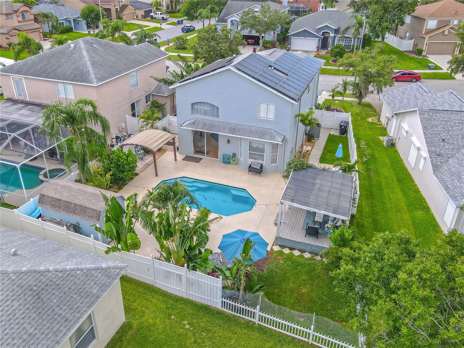 Fenced backyard with tropical landscaping, in-ground pool, pergola and storage shed