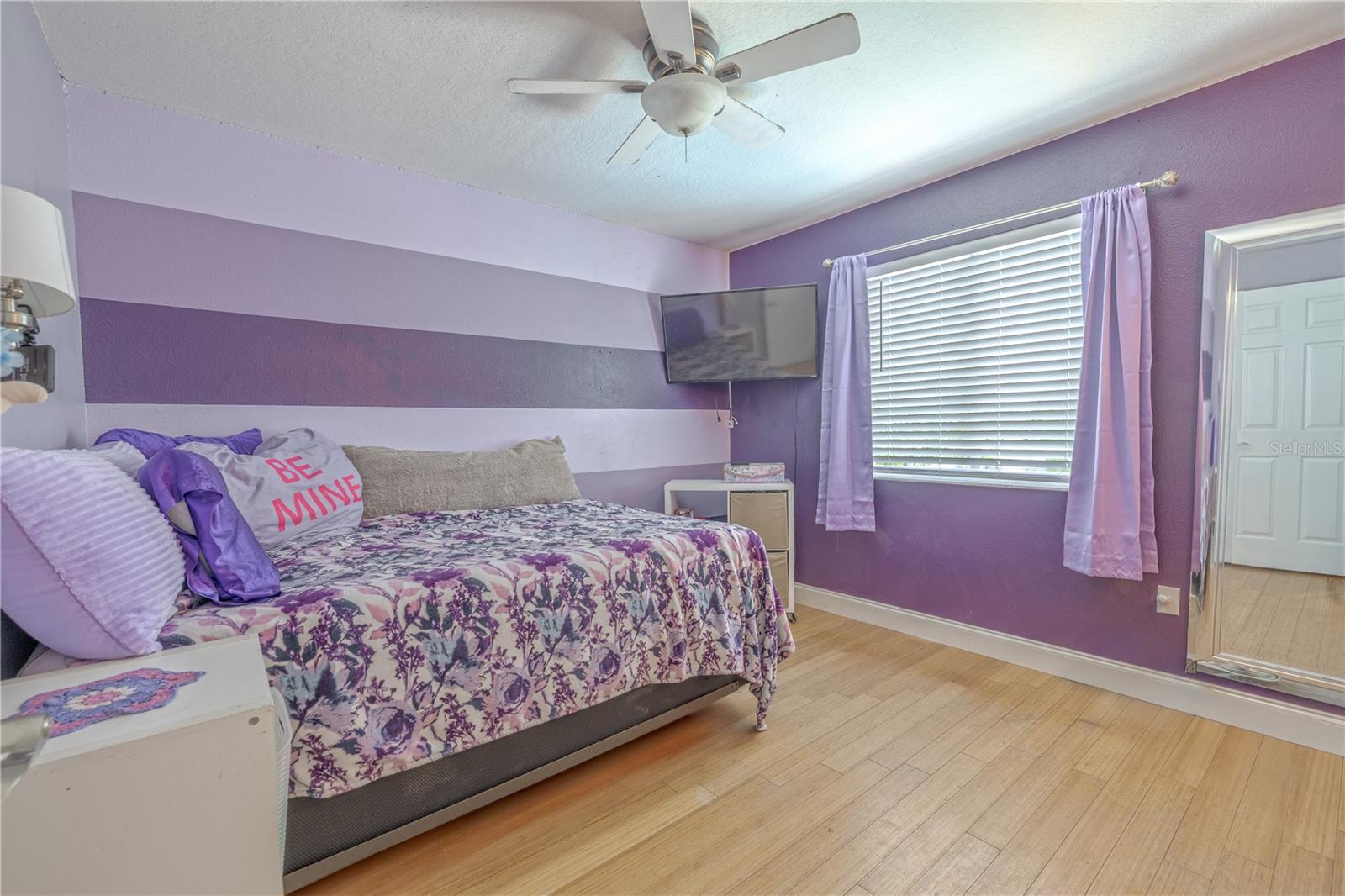 The third bedroom offers a comfortable and versatile space with ample natural light and a functional layout. A large window fills the room with soft daylight. Bamboo flooring continues throughout, adding warmth and consistency with the rest of the home.A ceiling fan with integrated lighting provides comfort and airflow.