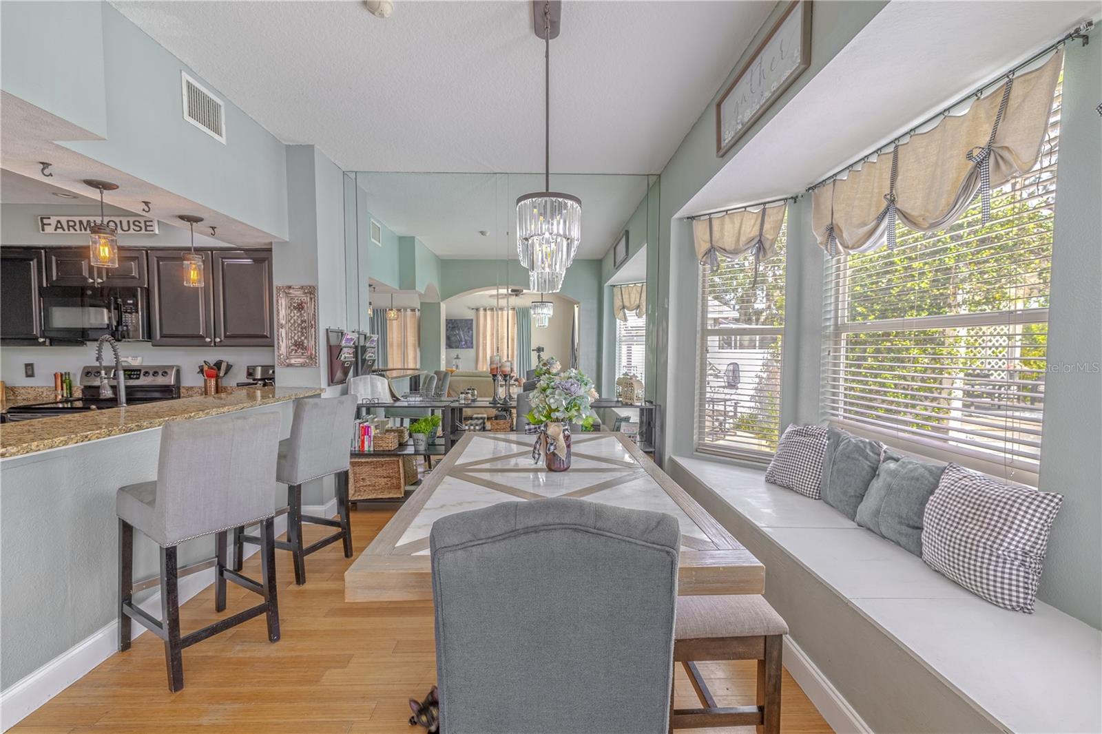The dining area is filled with natural light, thanks to a wall of windows and a charming bay window that offers an inviting architectural focal point. This light-filled alcove is ideal for a built-in bench or cozy breakfast nook.