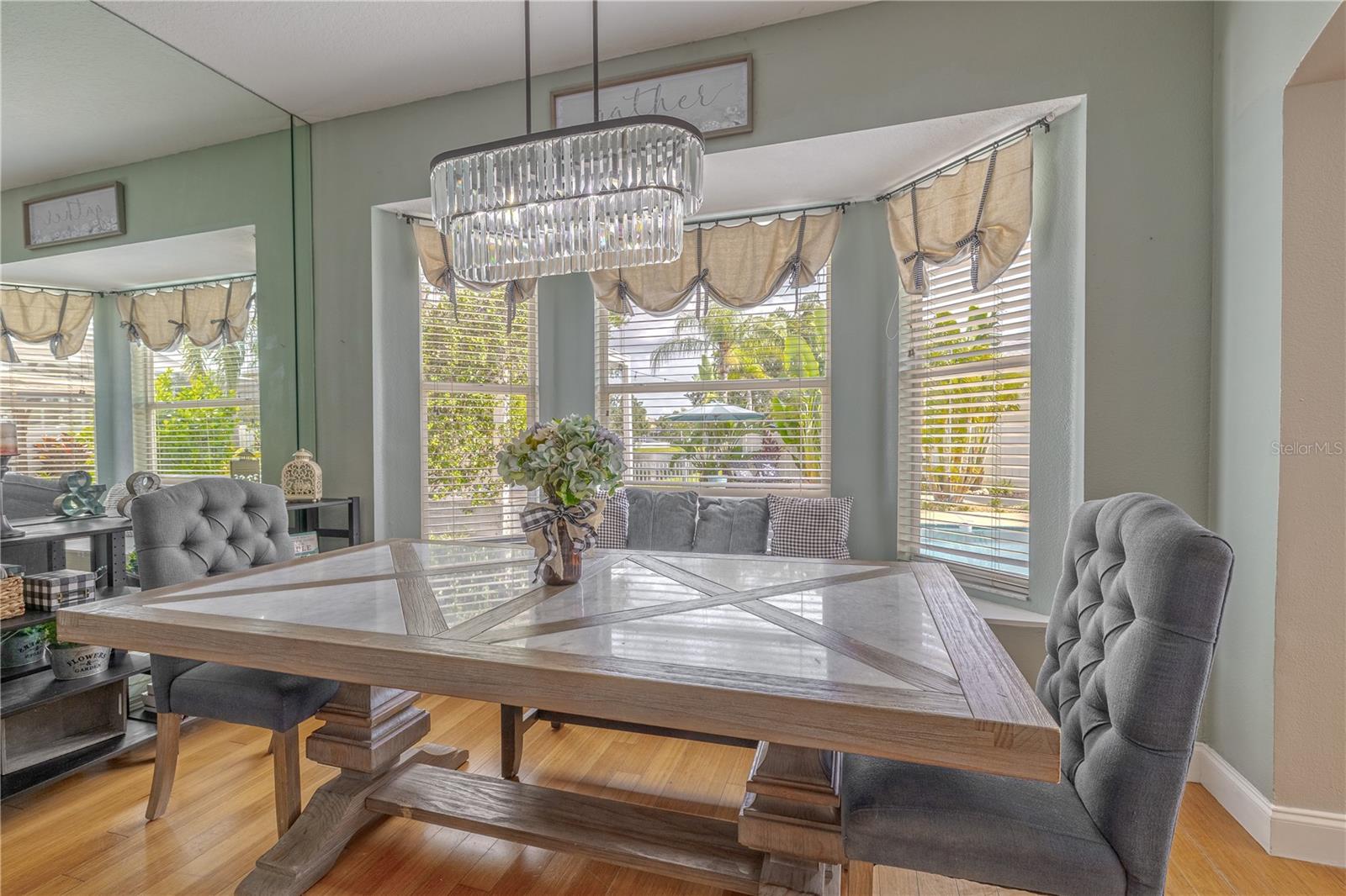 A mirrored accent wall enhances the sense of space and brightness, while a modern, pendant chandelier adds an upscale design touch.