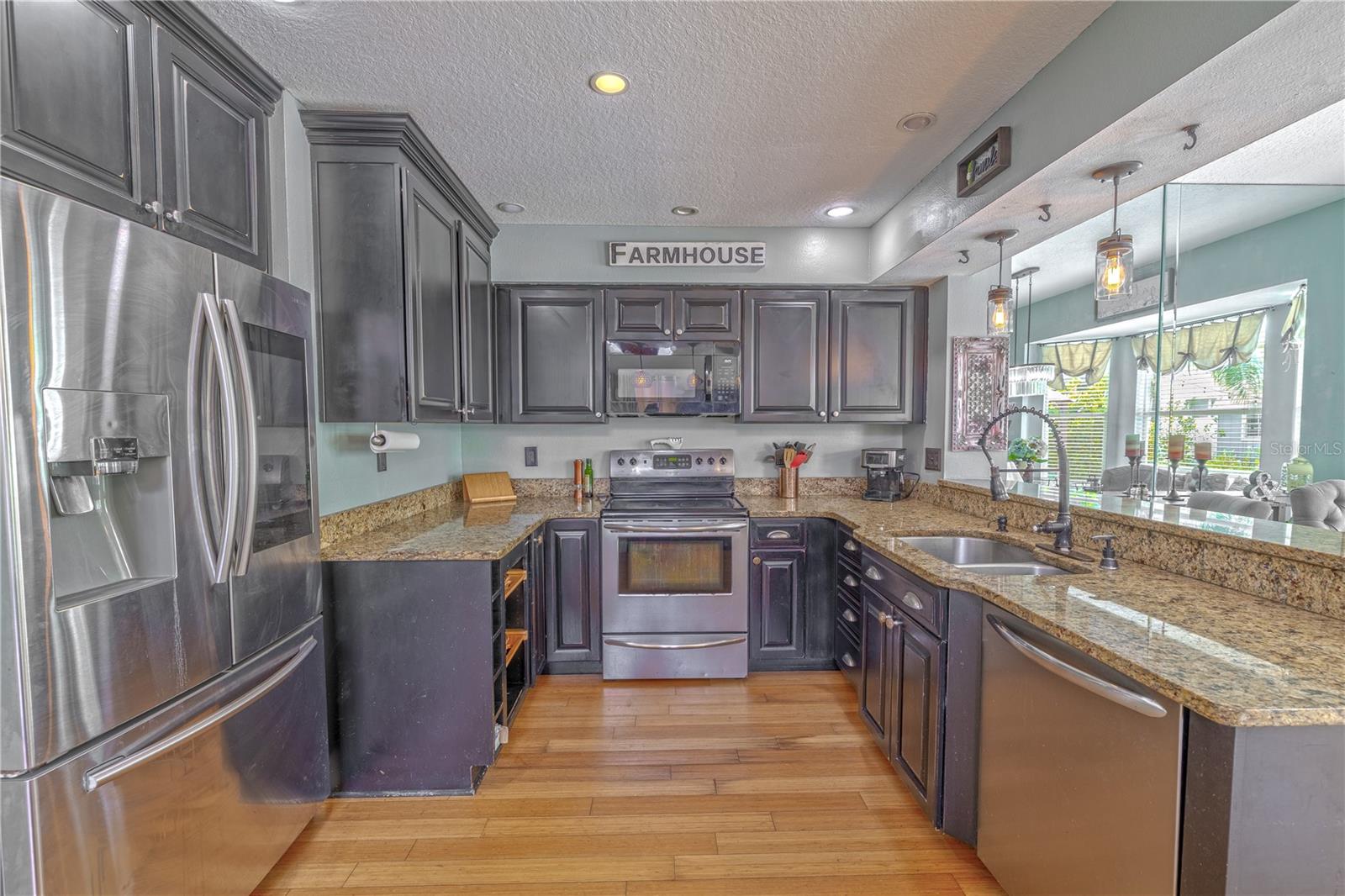 This thoughtfully designed kitchen blends functionality with timeless appeal, featuring solid wood cabinetry finished in a dramatic espresso tone that contrasts beautifully with the light granite countertops.