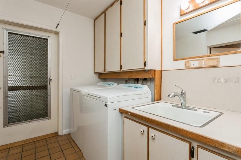 Laundry room adjacent to bathroom with another door to garage