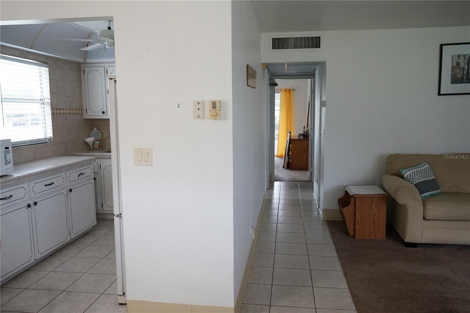 entry with dining and kitchen on the left and living space tot he right, hallway goes to the bedrooms