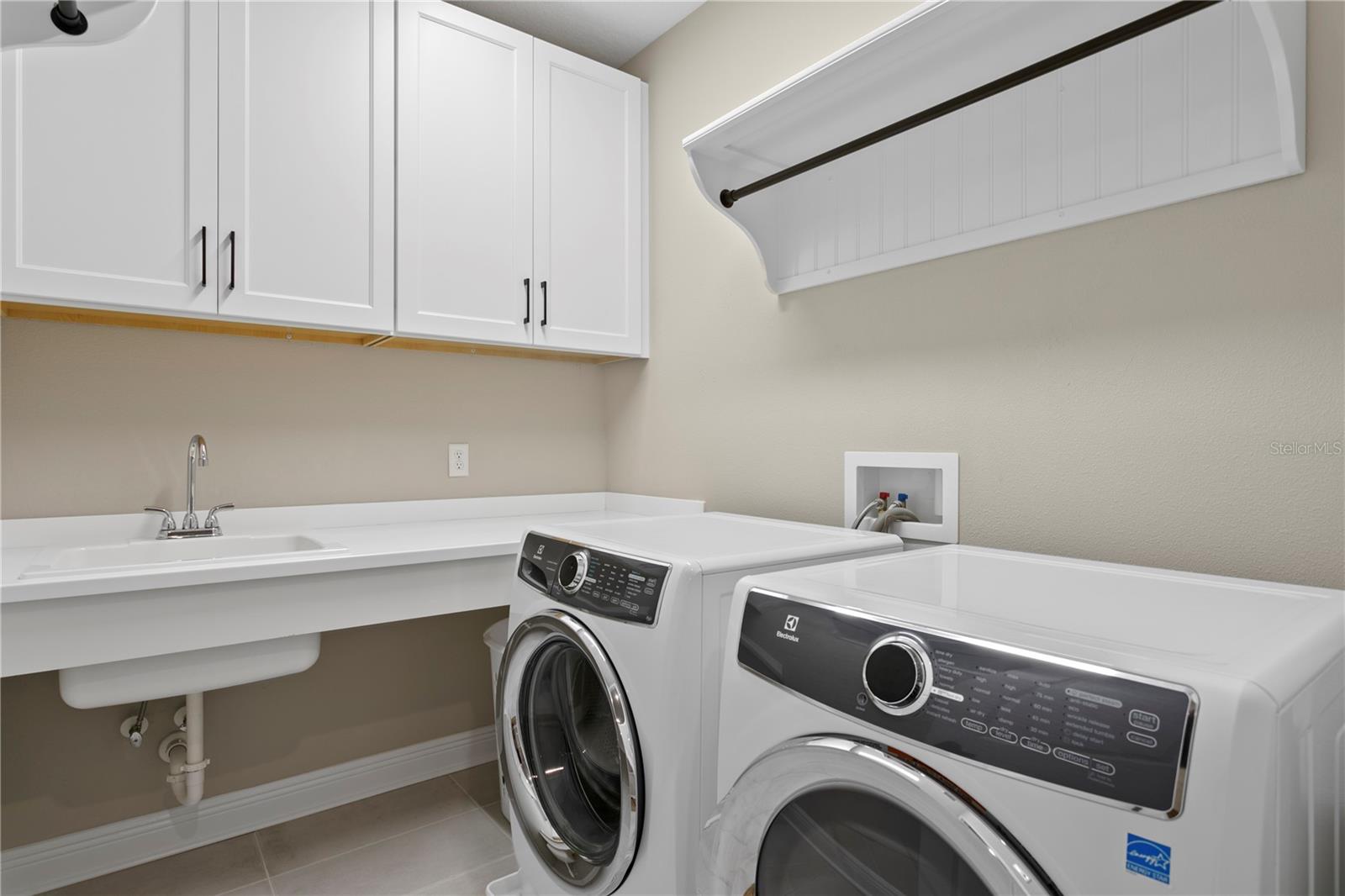The 2nd floor laundry room is complete with plenty of storage, space to hang clothes and a convenient utility sink.