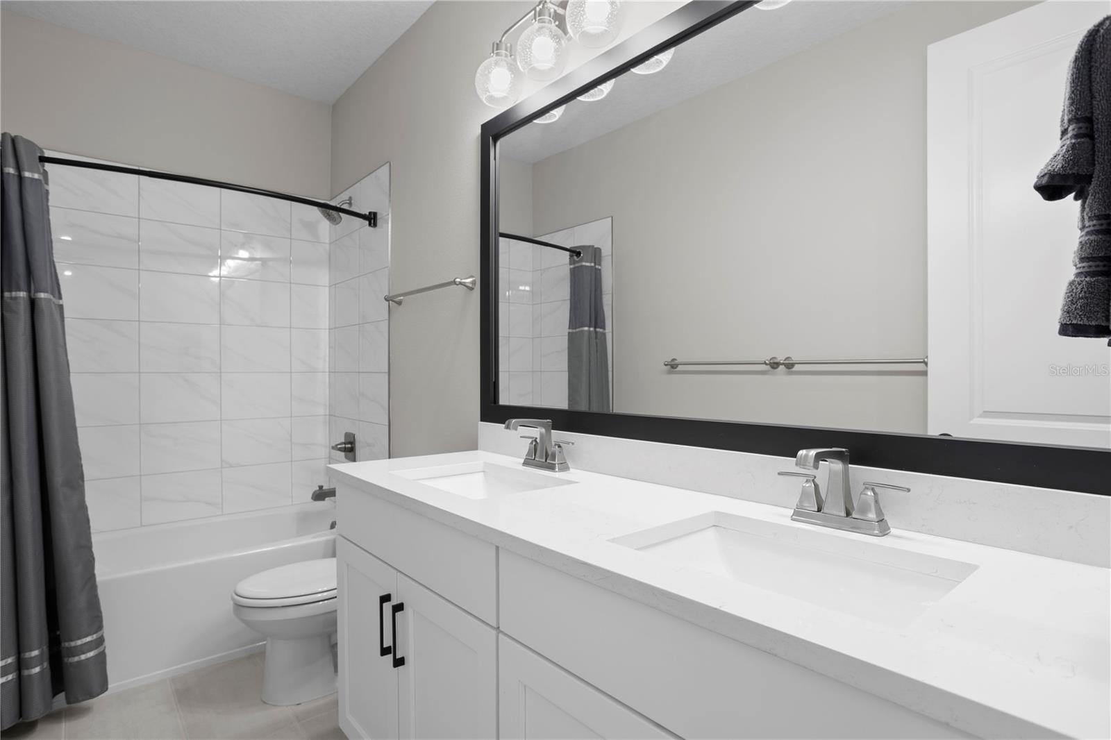 The spacious upstairs hall bathroom features dual sinks and beautiful finishes.