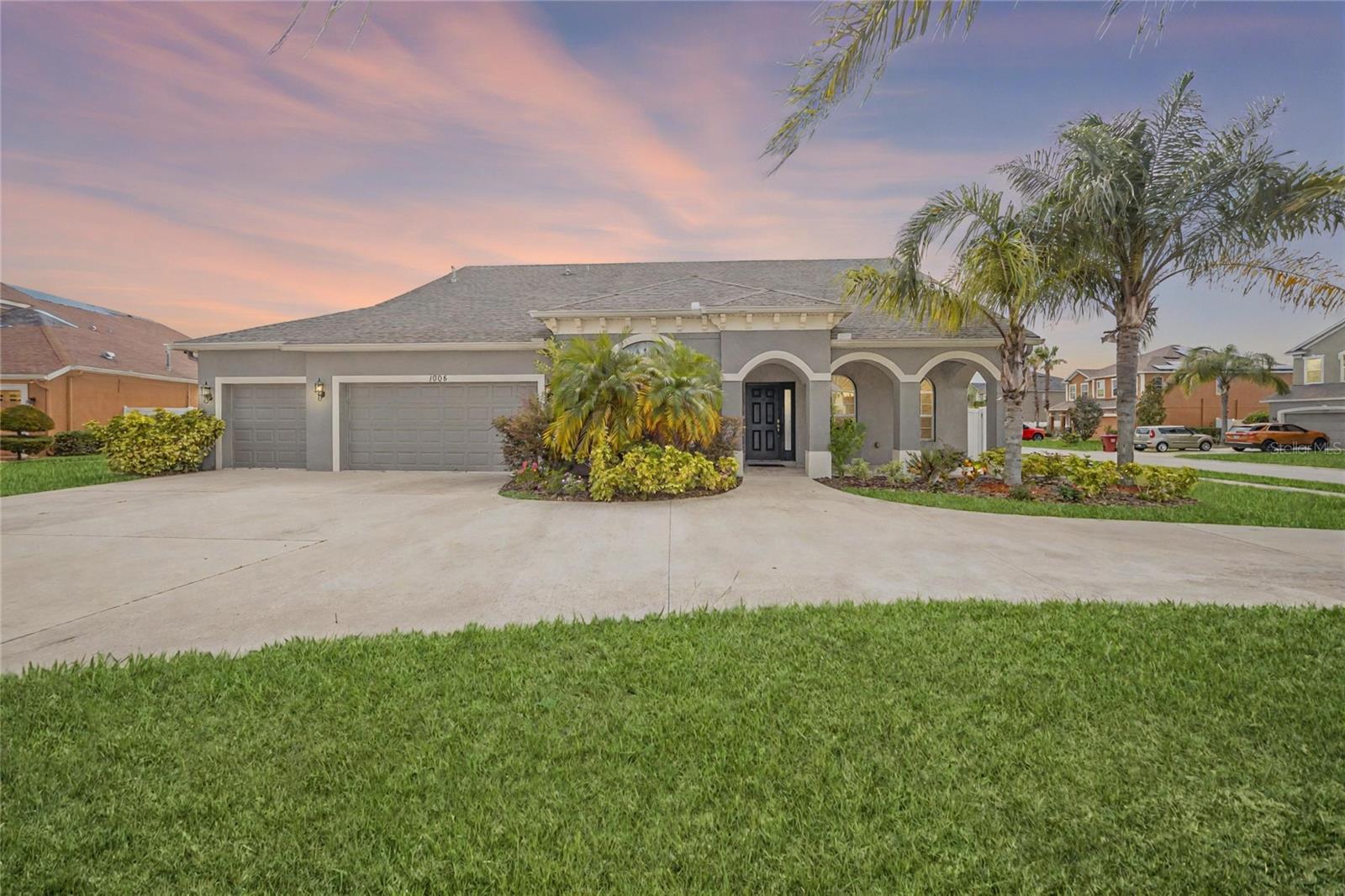 Front exterior with lush landscaping and spacious driveway