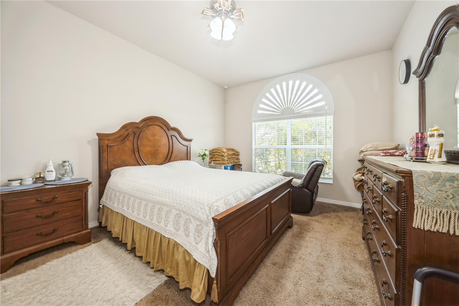 Primary bedroom with vaulted ceiling and large window