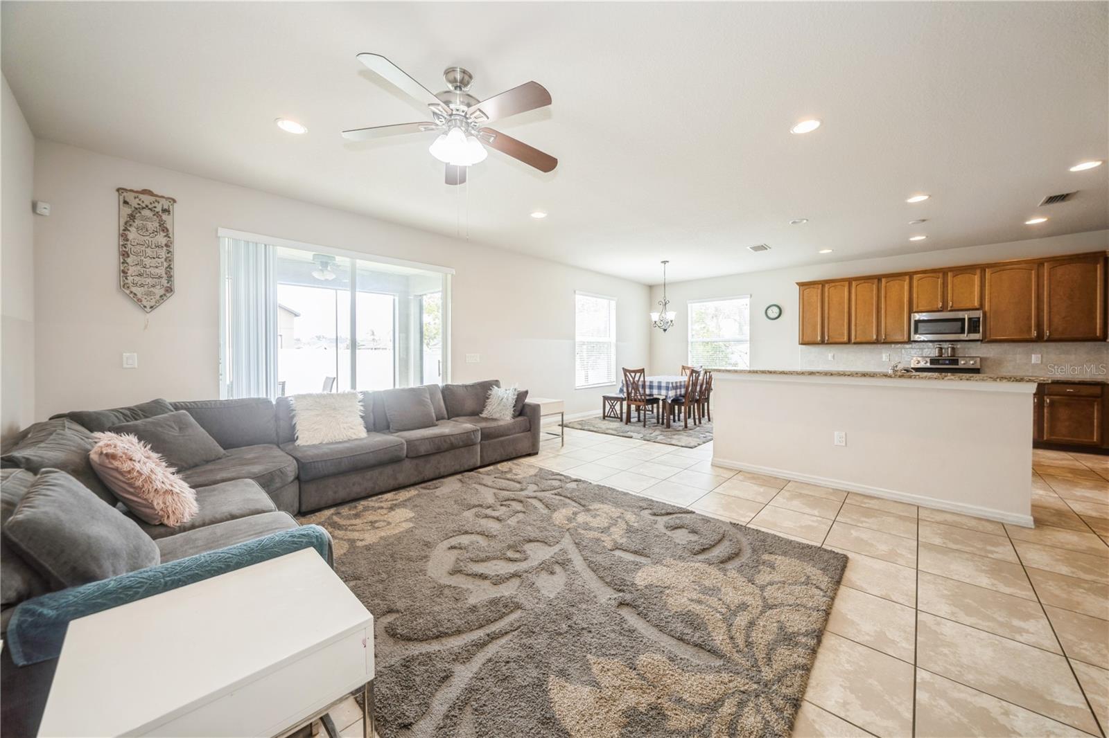 Open-concept living area with natural light, tile flooring, and seamless flow into the kitchen.