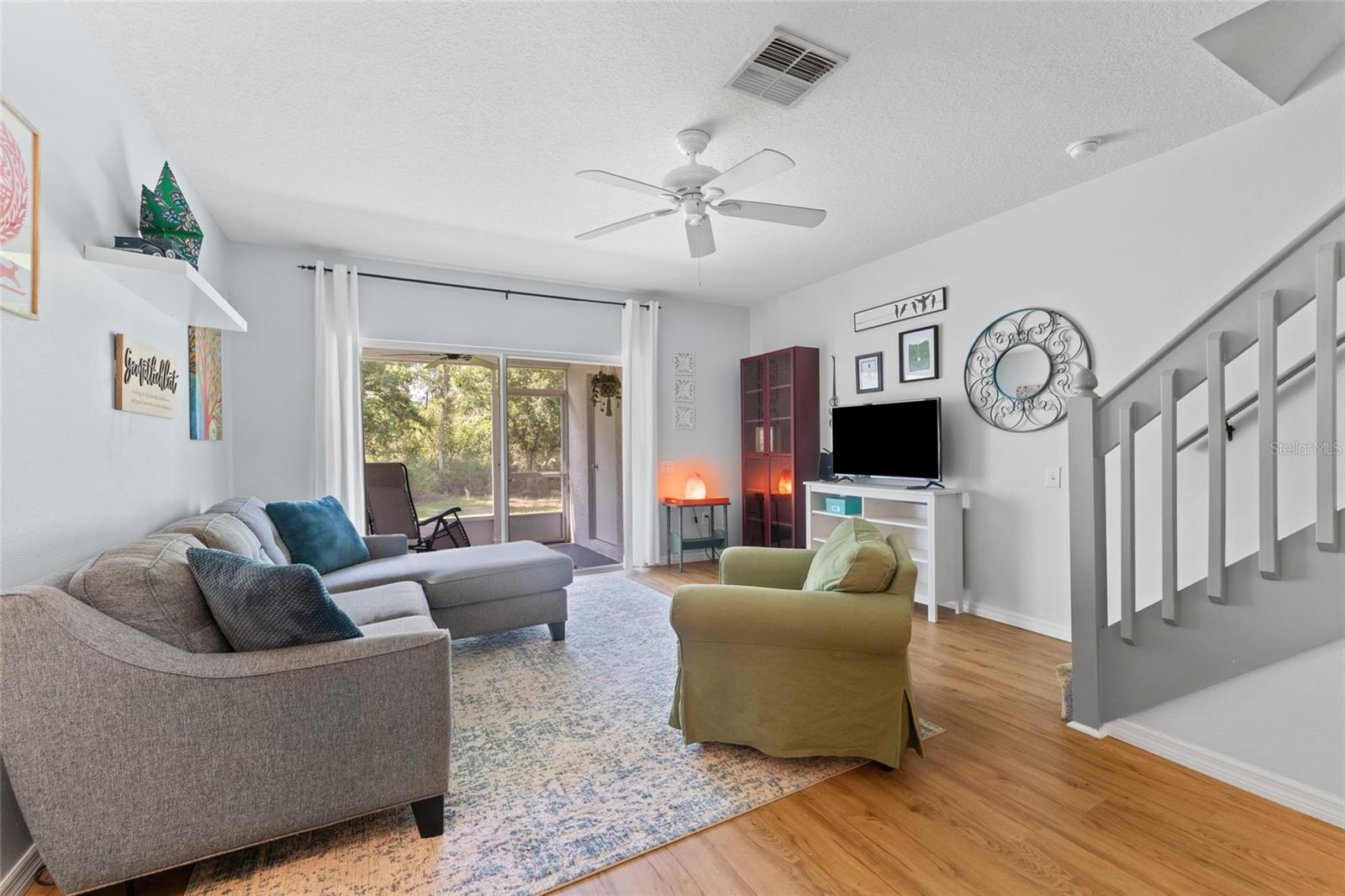 Living area w/wood laminate flooring and serene conservation view from screened porch. Tasteful decor.