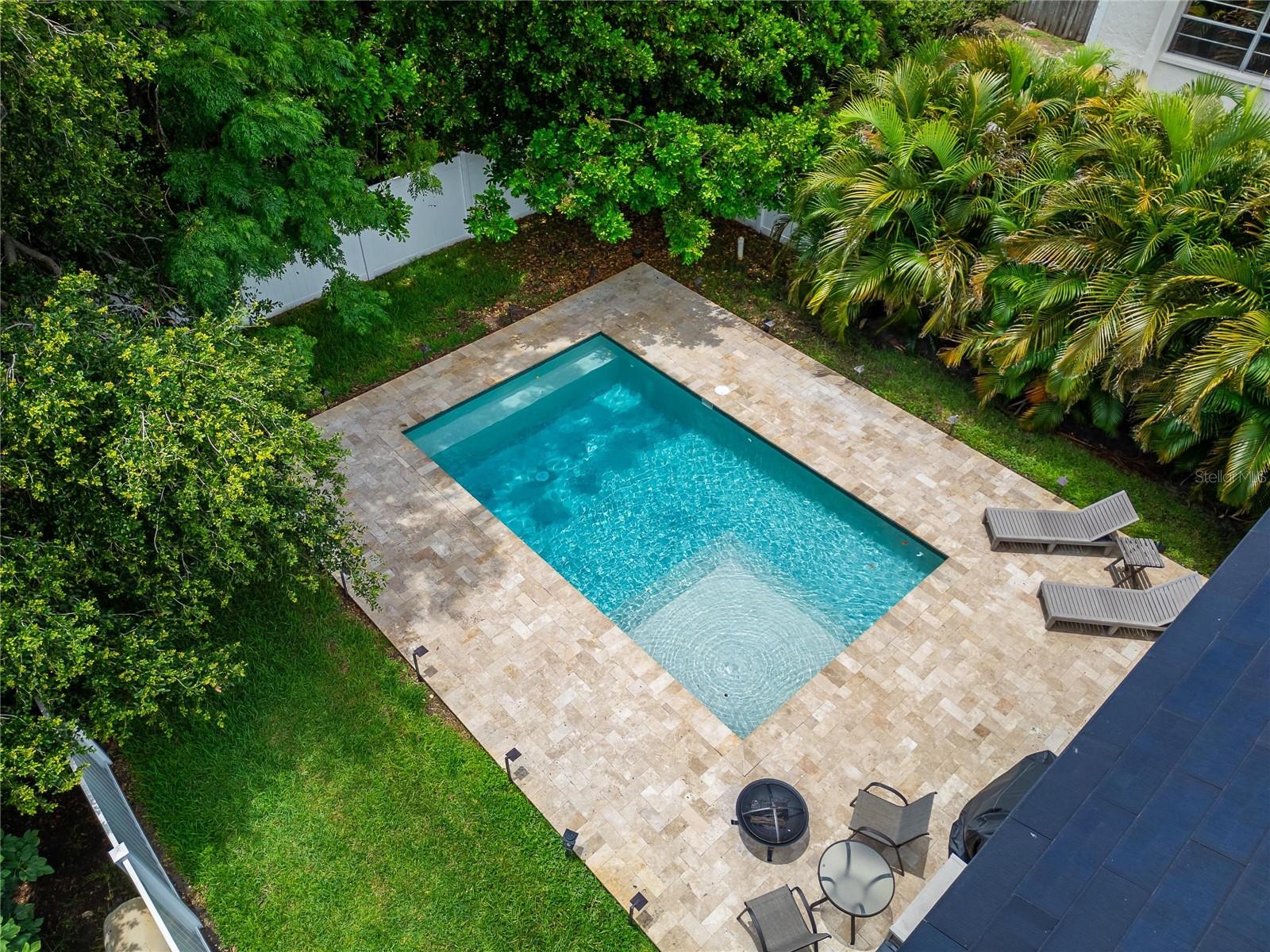 Surrounded by lush, professionally landscaped greenery, swaying palm trees, and private vinyl fencing