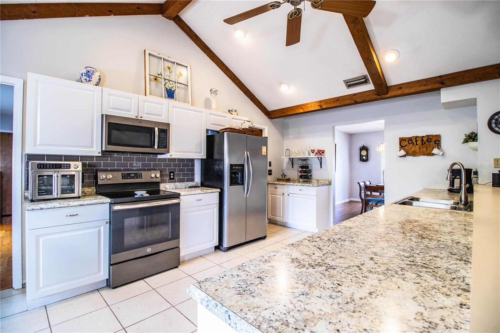 The kitchen features an expansive bar, coffee nook, modern finishes, and stainless steel appliances.
