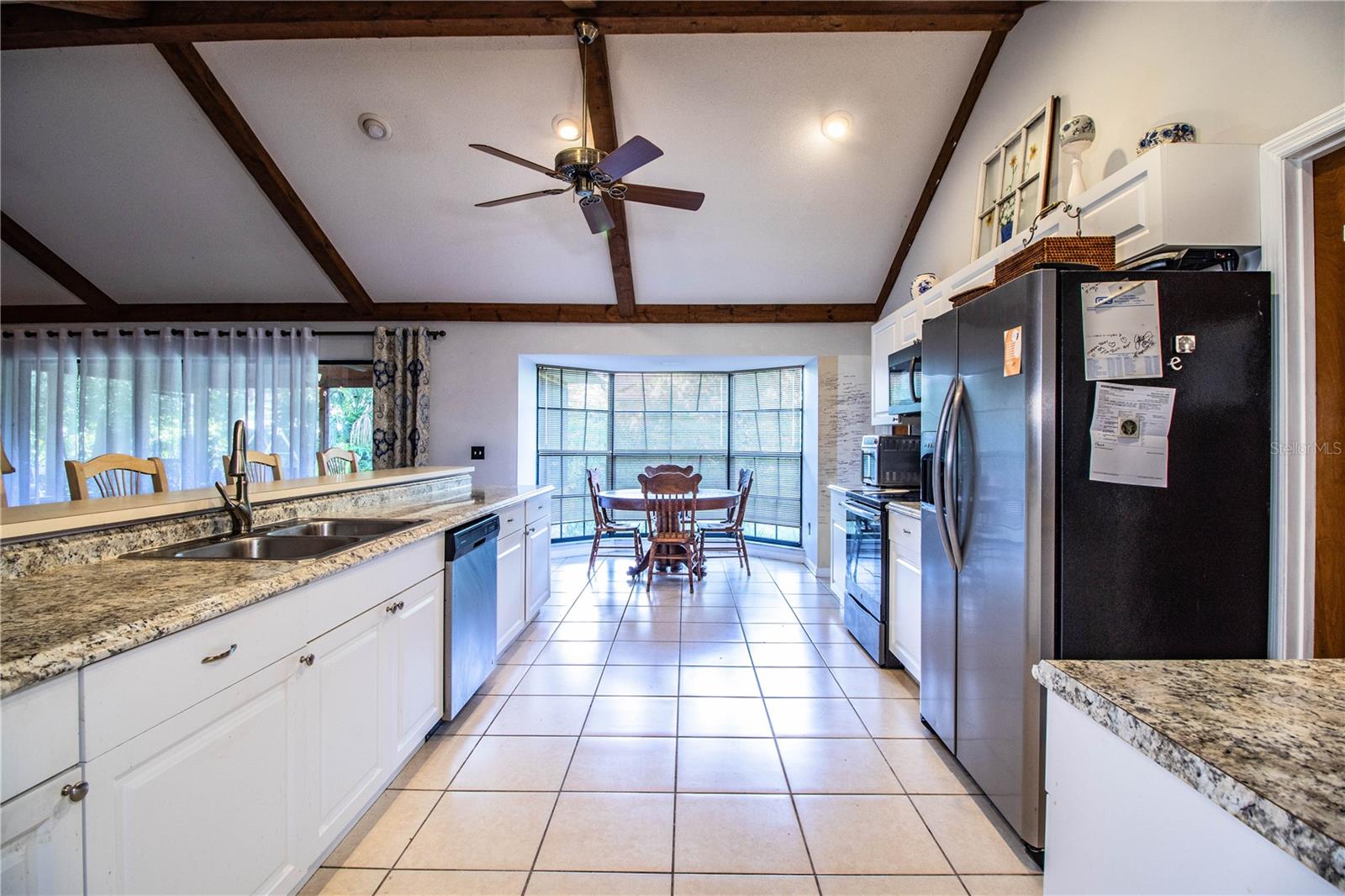 Spacious kitchen with tile floors, a dinette area, and large windows overlooking the yard.