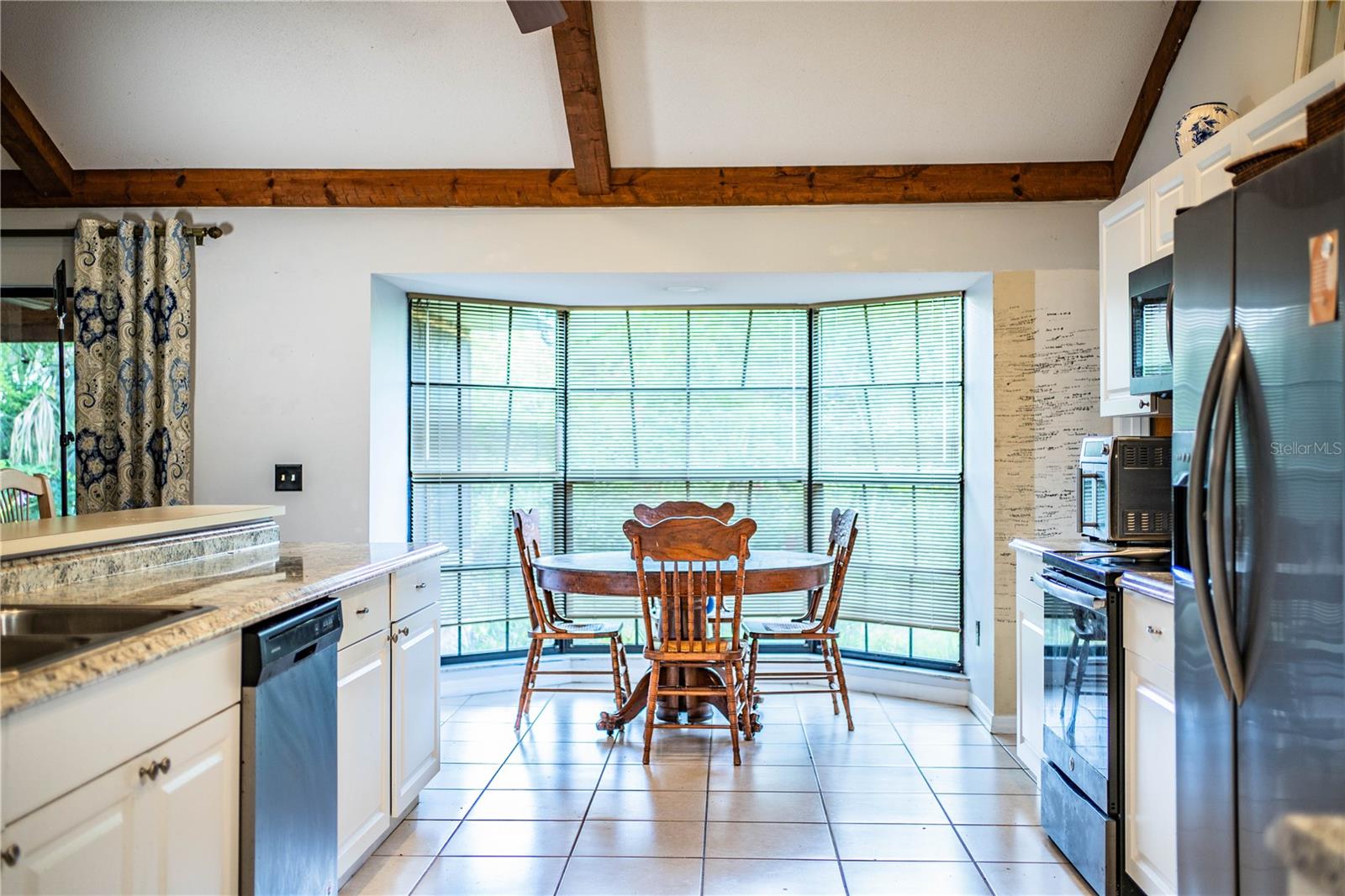 Charming dinette with bay window overlooking the lush backyard oasis.