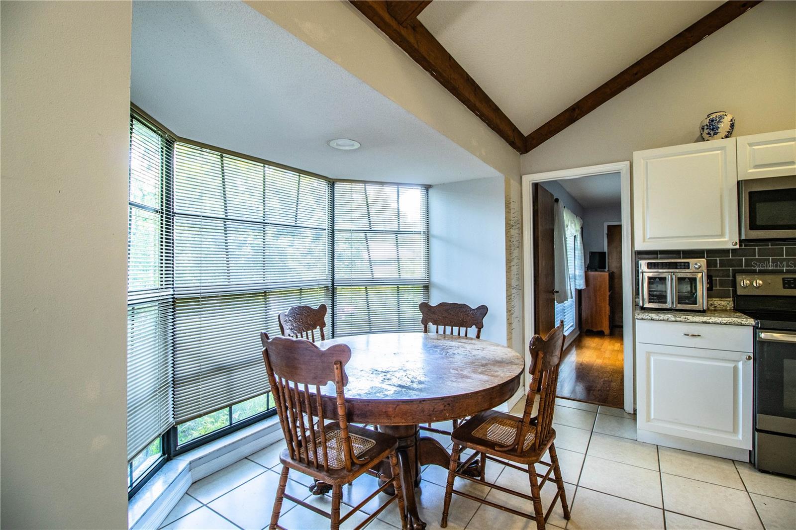 Cozy dining nook with natural light pouring in from a wide bay window and backyard views.