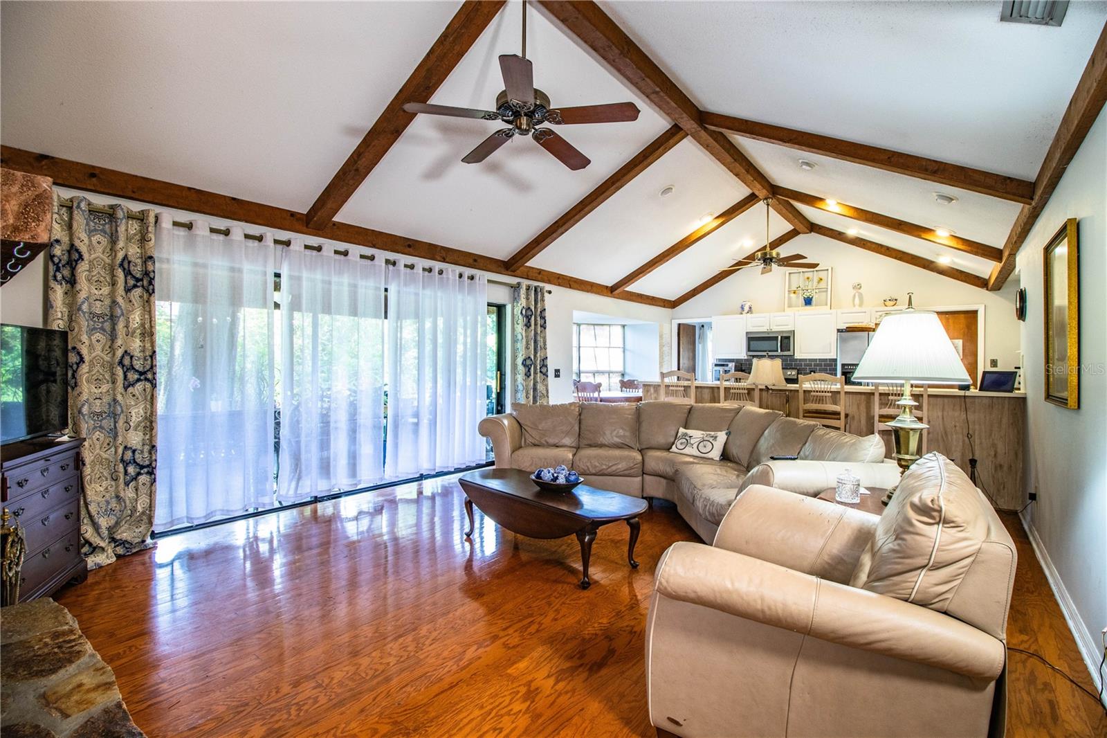 Spacious family room flows seamlessly into the kitchen, highlighted by ceiling beams.