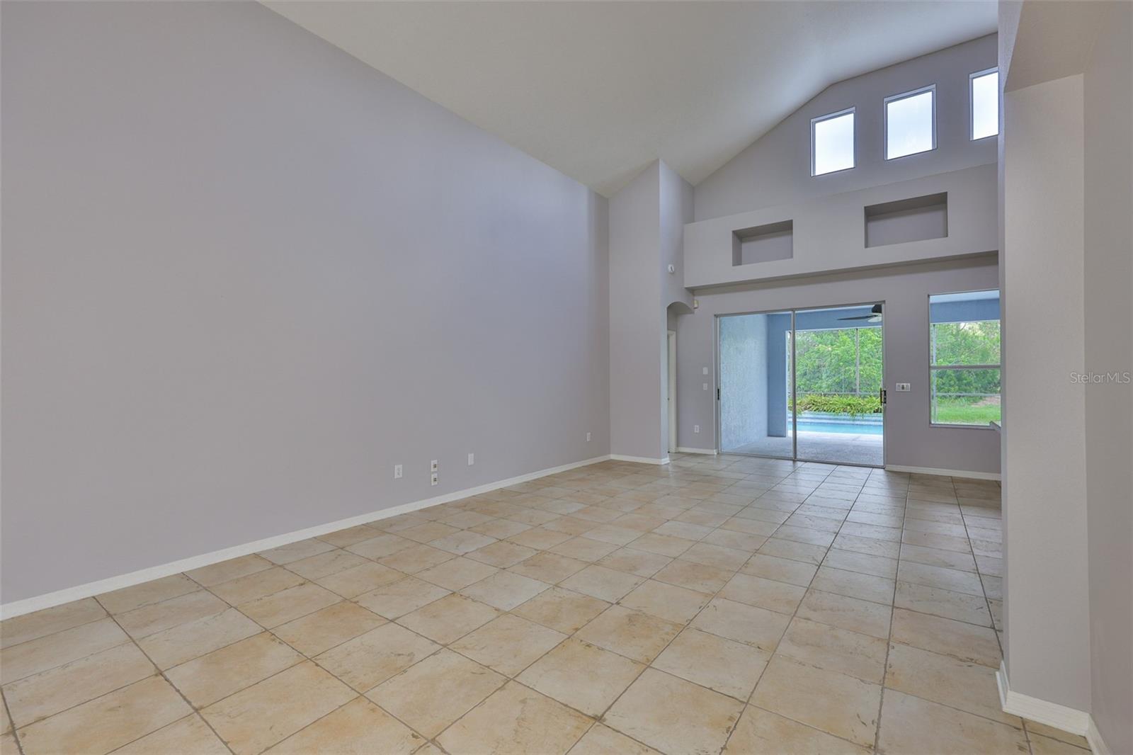 Great room with sliders and pool view, primary bedroom entrance far left