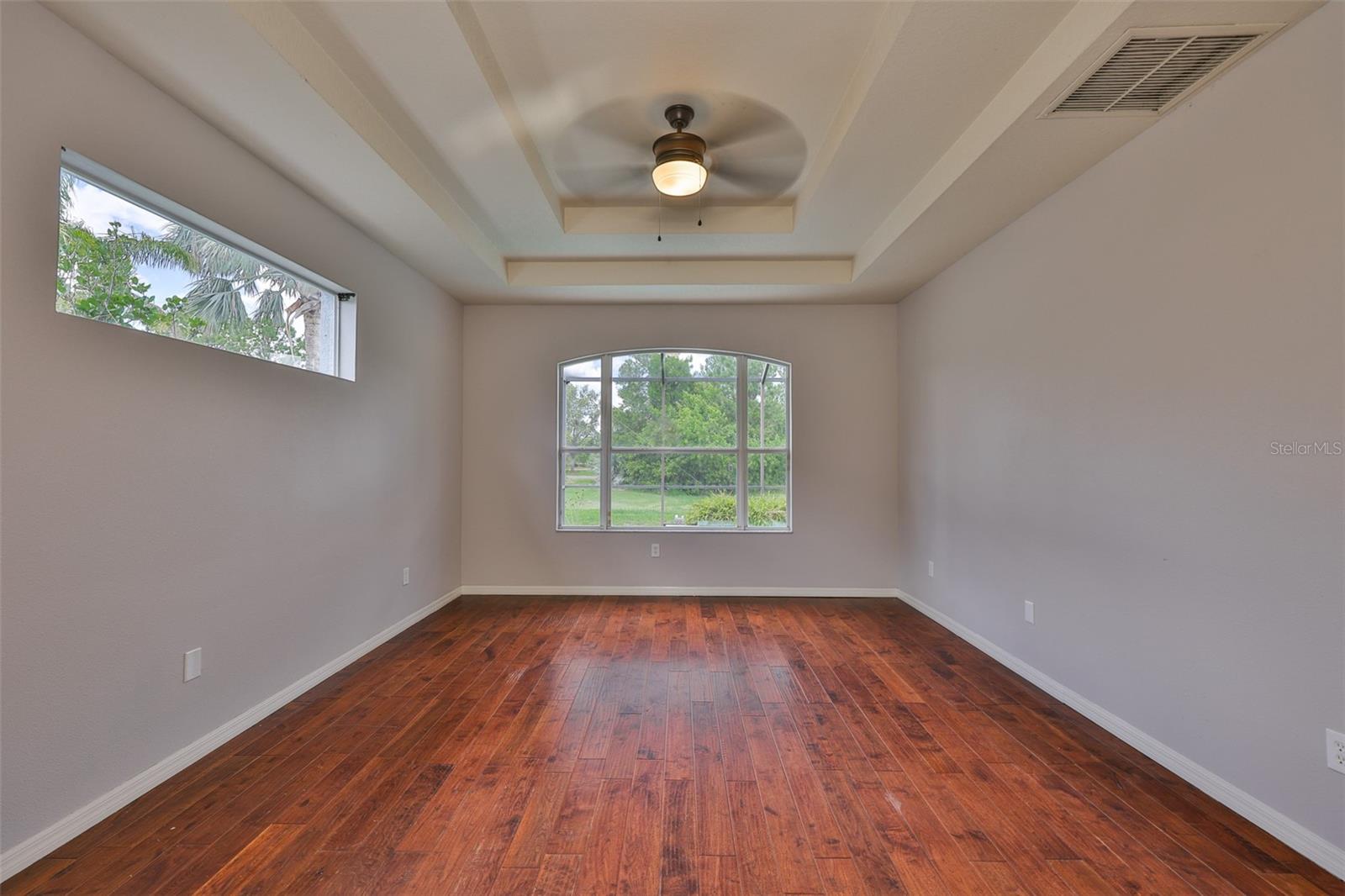 Primary bedroom suite with engineered hardwood, ceiling fan, window wall, water view, pool view and double trey ceiling.