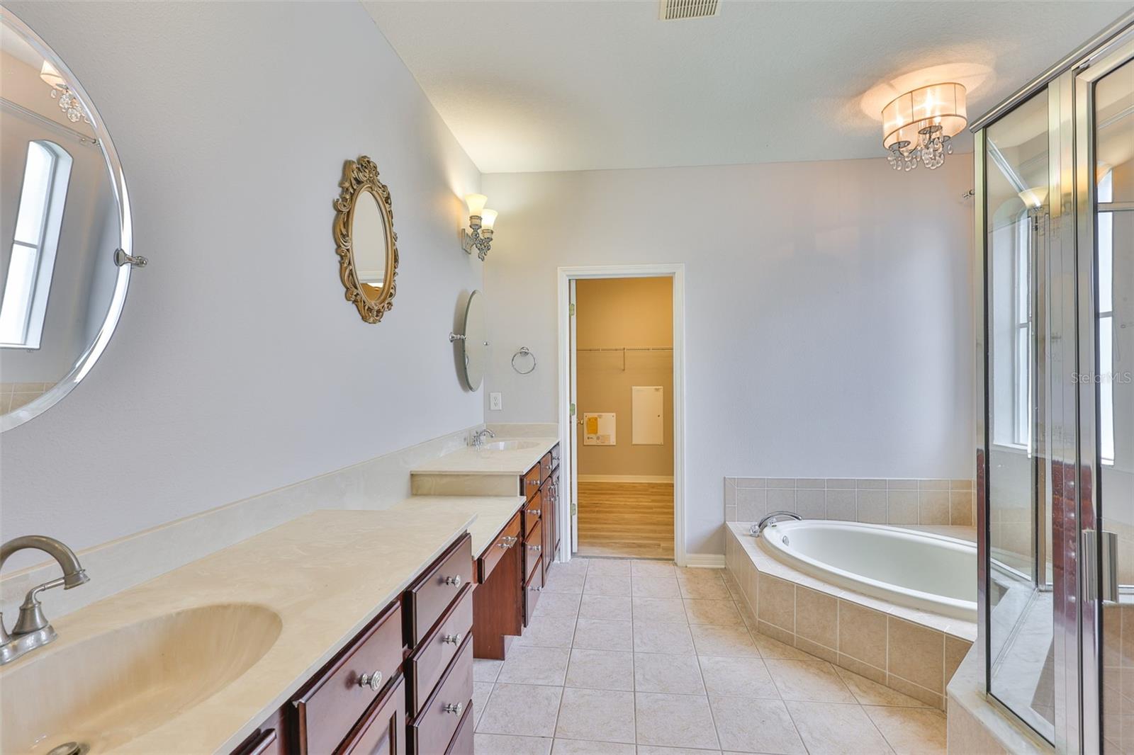Primary bath with split vanities, private water closet, linen closet, make up area, low height garden tub, window and separate glass enclosed stall shower. Huge walk-in closet in rear
