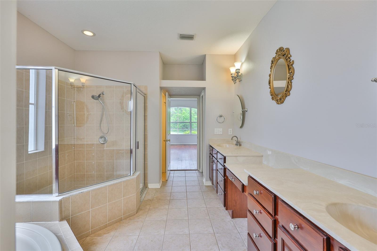 Primary bath with split vanities, private water closet, linen closet, make up area, low height garden tub, window and separate glass enclosed stall shower. To primary bedroom in rear