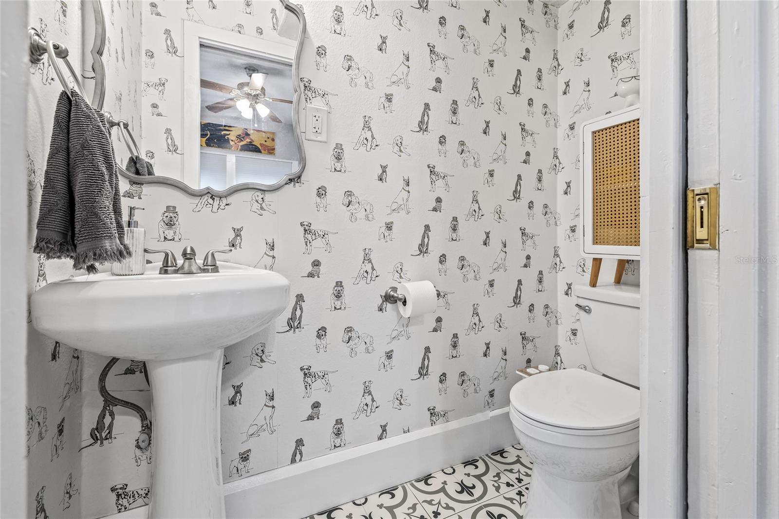 This whimsical main floor half bath, features a pedestal sink and patterned tile flooring—full of charm and character.