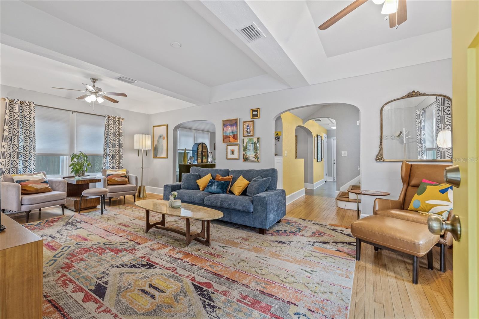 Spacious and light-filled living area featuring hardwood floors, and tray ceilings.
