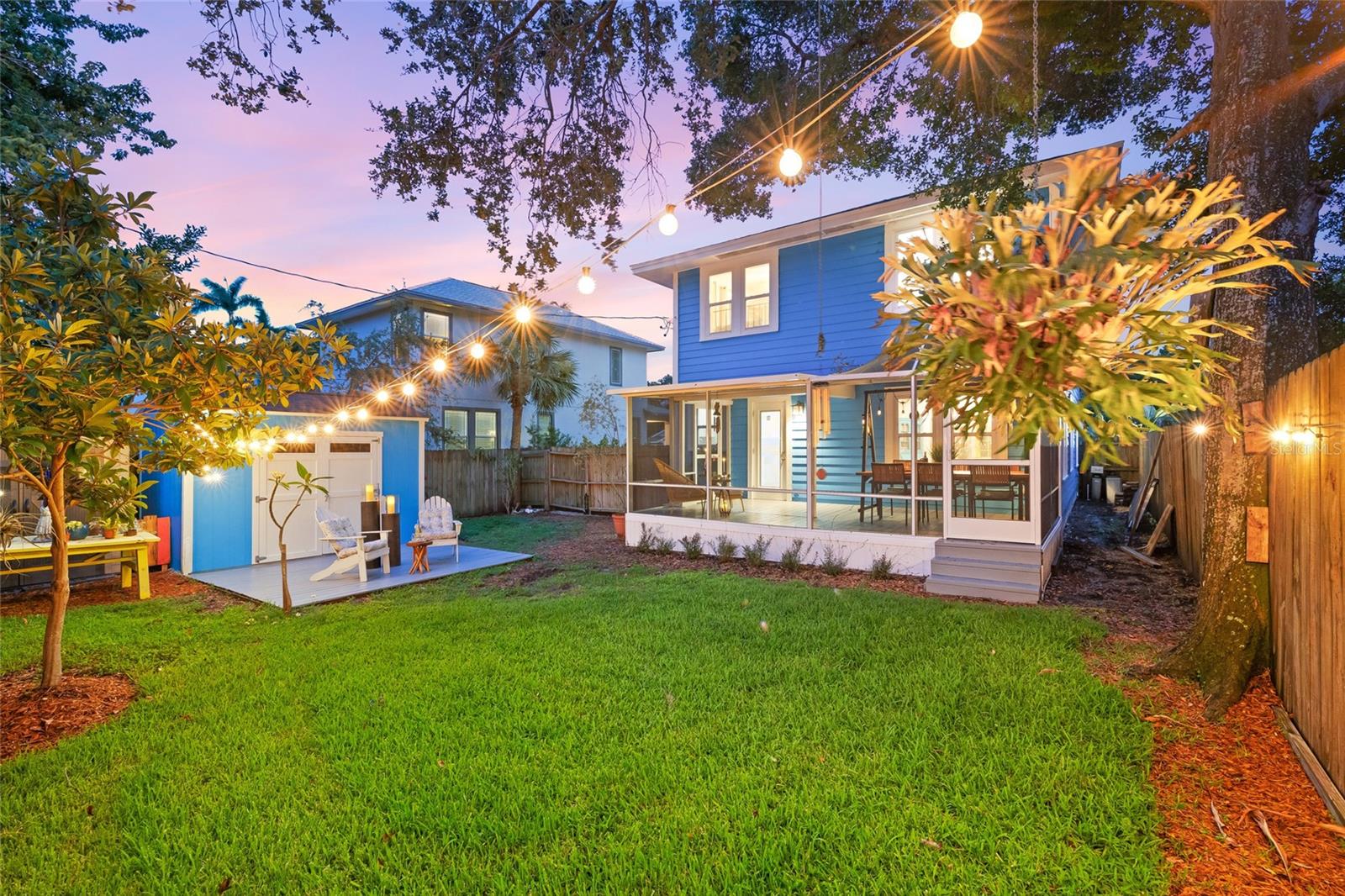 Warm string lighting and vibrant landscaping create a magical setting perfect for evening gatherings or quiet reflection.