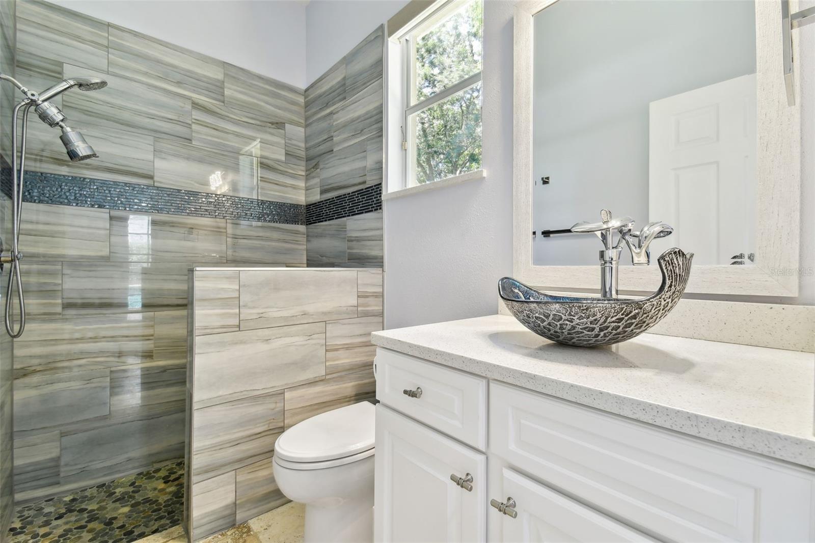 Custom in-law suite featuring a remodeled full bathroom with direct exterior access to the pool and lanai.