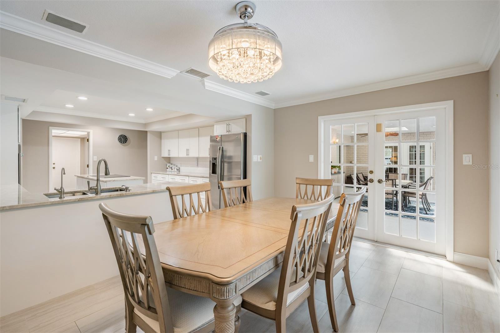 The adjacent breakfast area easily accommodates a full-size table. French doors and a large window create an indoor-outdoor connection while framing beautiful views of the pool area and vibrant tropical landscaping.