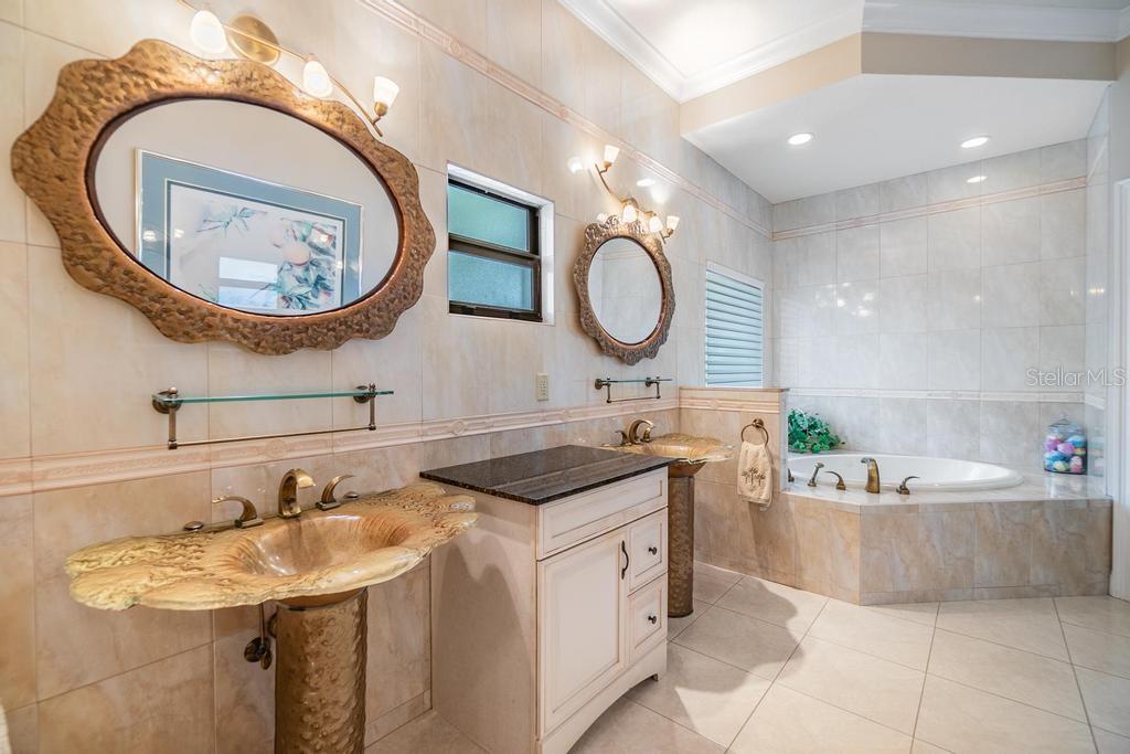 The stunning spa-inspired ensuite bath is designed to impress with dual designer stand-alone vanities, a luxurious Jacuzzi tub, a separate walk-in shower, a private toilet room, and sparkling tile finishes that add a touch of elegance to this relaxing sanctuary.