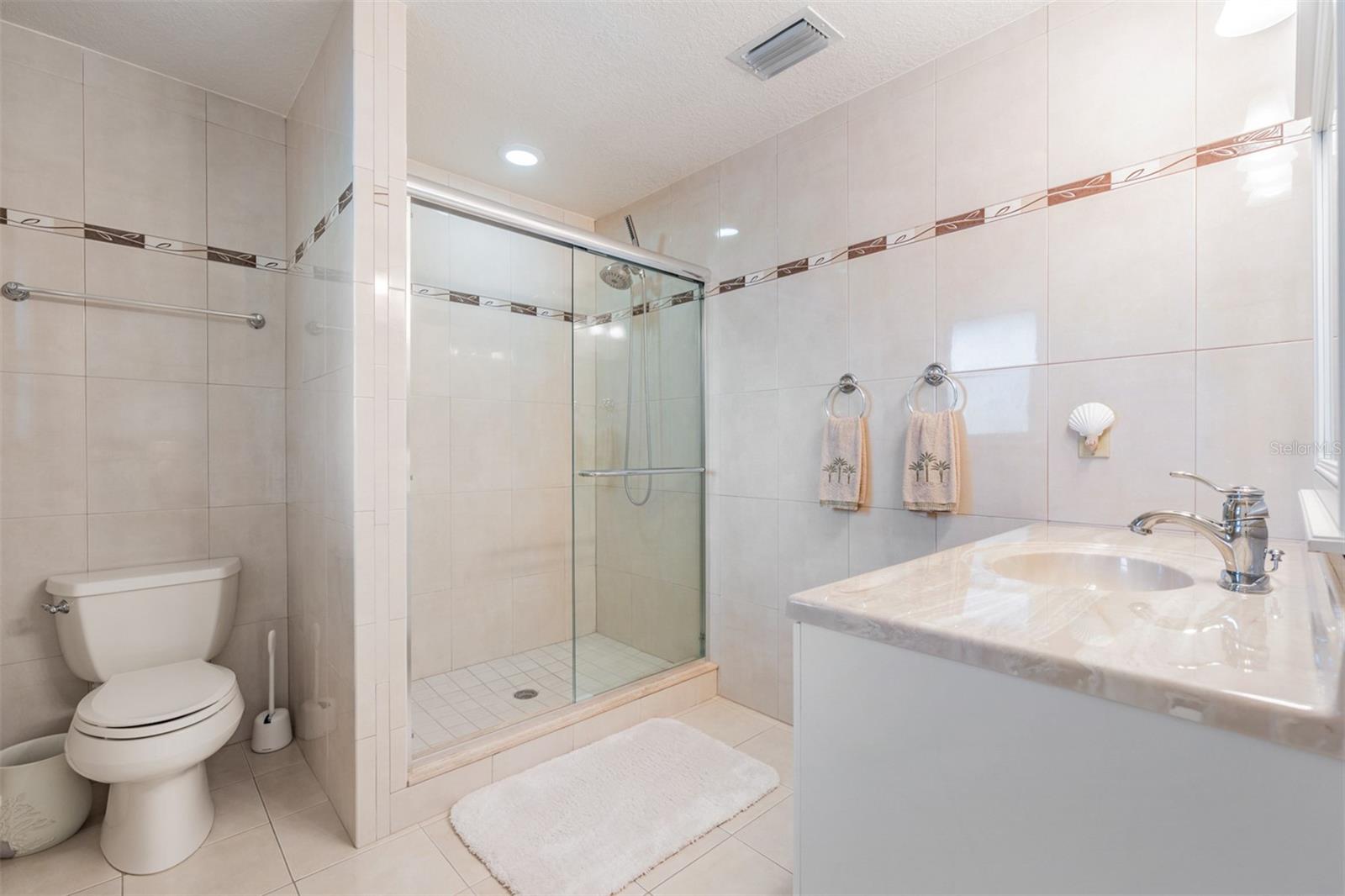 Located across from the primary suite, the fourth bedroom is perfect for guests or a nursery, boasting its own ensuite bath with stylish finishes and a convenient stand-up shower.