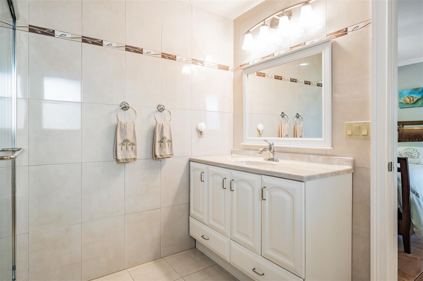 Located across from the primary suite, the fourth bedroom is perfect for guests or a nursery, boasting its own ensuite bath with stylish finishes and a convenient stand-up shower.