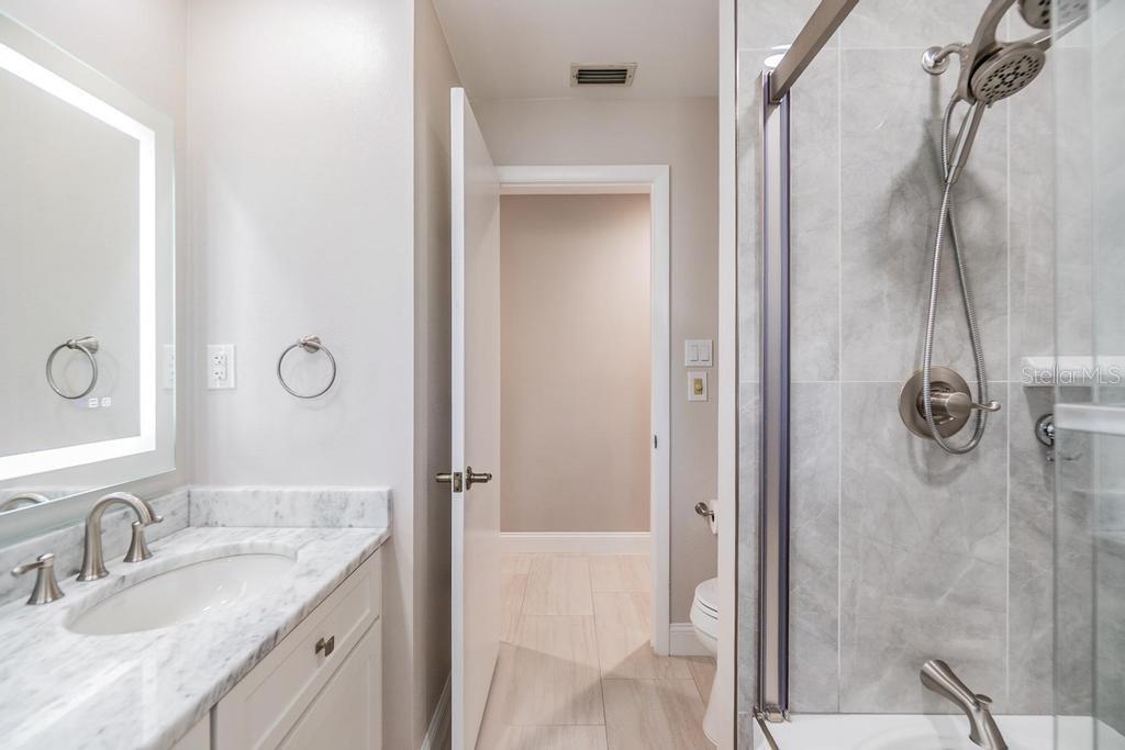 Beautifully updated bathroom featuring a marble-topped dual-sink vanity and a tub/shower combination