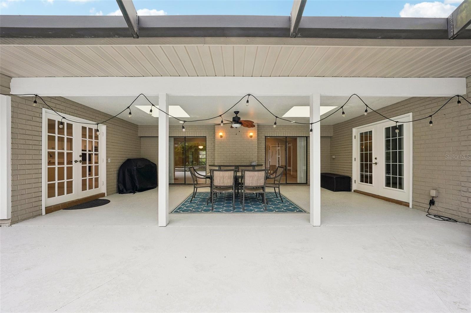 Step outside to the expansive pool deck, where a covered seating area with skylights and a ceiling fan creates the perfect spot to unwind. Surrounded by lush tropical landscaping, the sparkling Gulfstream saltwater pool features a gleaming pebble sheen finish, self-cleaning system, and a tranquil spillover spa with fountain.