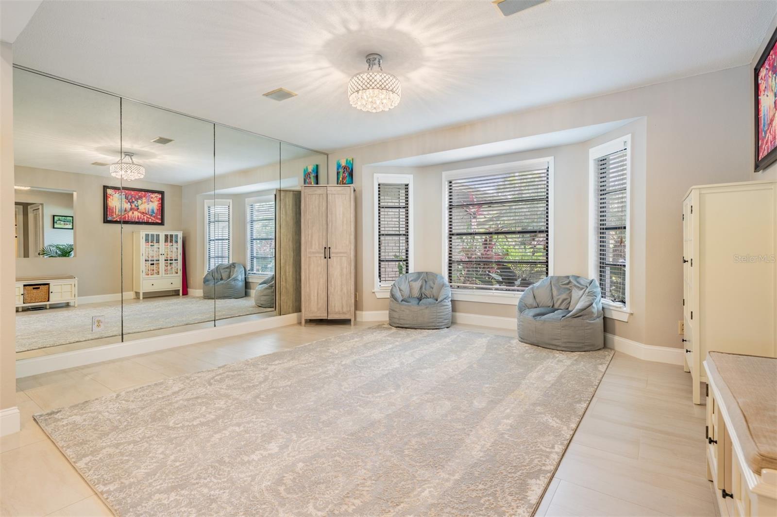The formal dining room exudes warmth and elegance, with large bay windows that fill the space with natural light and a mirrored wall that enhances the radiant atmosphere. These beautifully designed spaces are perfectly suited for both relaxed family time and upscale entertaining.