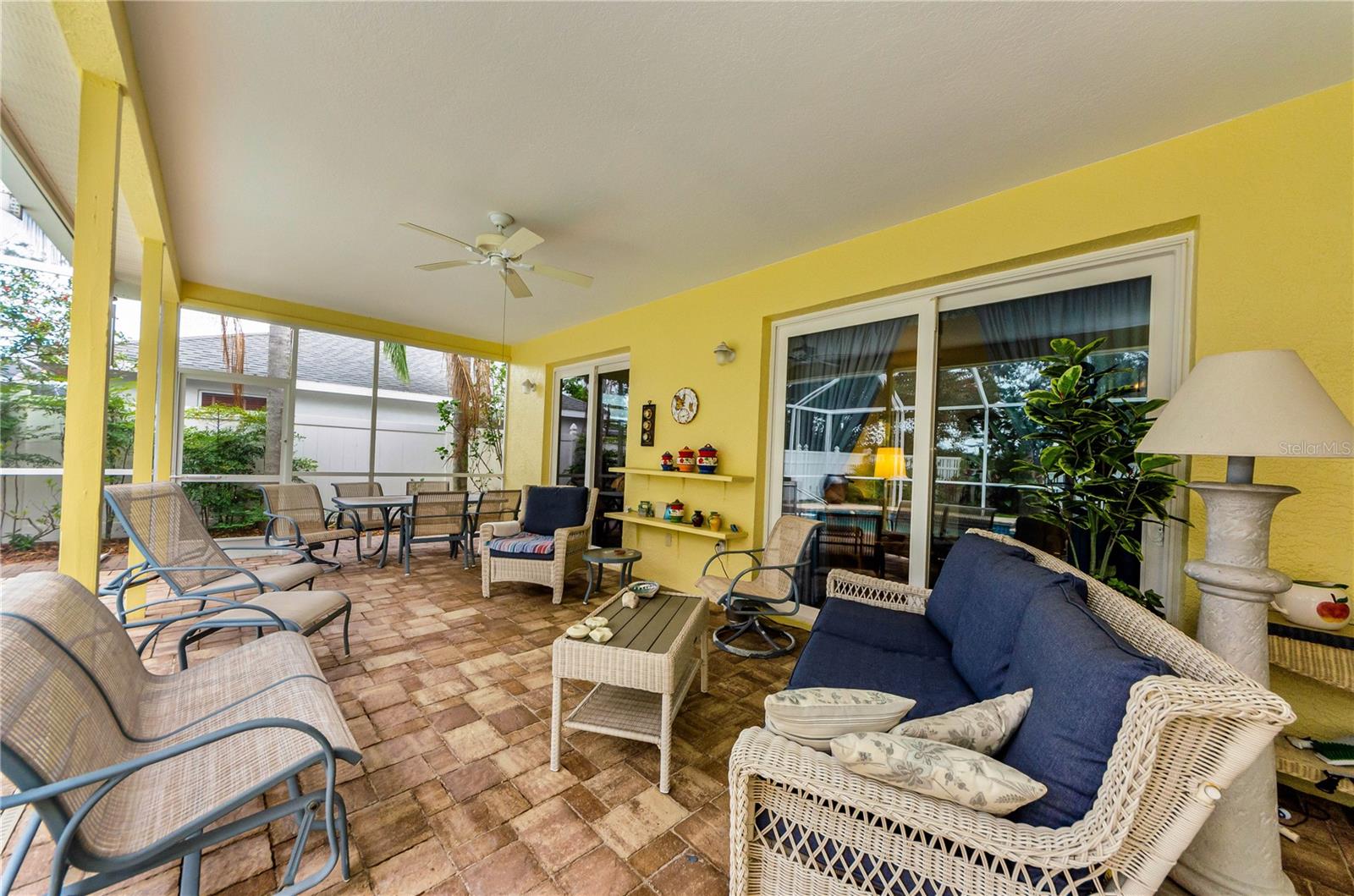 Patio pavilion area with paver brick flooring overlooking pool and backyard.  Sliding doors from primary bedroom, living room, family room and access to bathroom off bedroom #2 hallway.