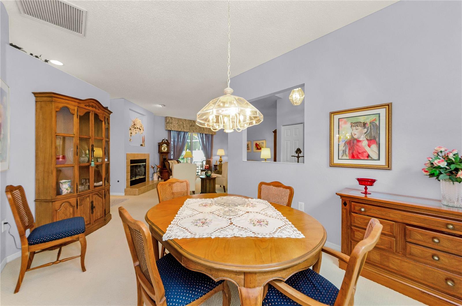 View of dining room looking through to living room with fireplace and out glass sliding doors to pool area.