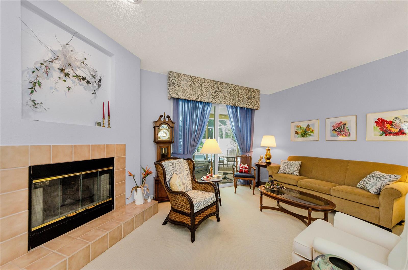 Open view of living room and two sided fireplace out through glass sliders to pool area.  High ceilings throughout.